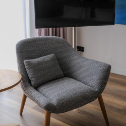 Poltrona estofada cinza com pés em madeira